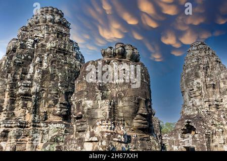 Coucher de soleil coloré sur les faces anciennes en pierre du temple de Bayon, Angkor, Cambodge Banque D'Images