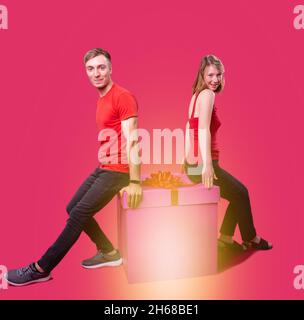 Beau jeune couple en vêtements rouges et jeans noirs assis sur la boîte à présent avec leurs dos les uns aux autres et ils sont heureux. Banque D'Images