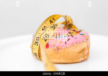 Gros plan sur le Donut et le ruban de mesure, la perte de poids et le concept de régime. Banque D'Images