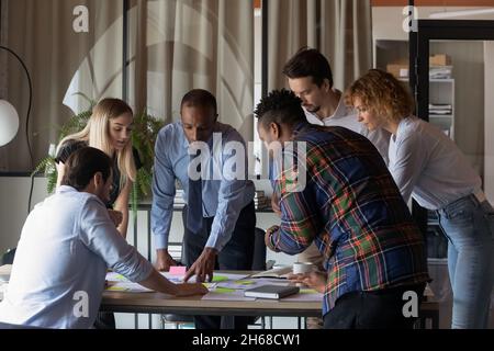 Des jeunes coéquipiers mixtes concentrés analysant des rapports papier. Banque D'Images