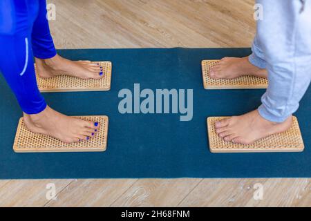 Photo en gros plan des pieds d'un couple debout sur des planches de Sahu avec des ongles tranchants.Concept de pratique du yoga. Banque D'Images