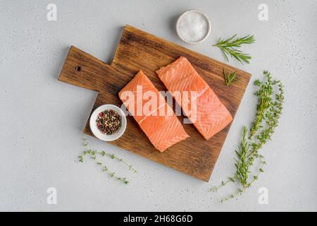 Filet de saumon scandinave frais brut.Romarin et thym.Sel et poivre.Sur une ancienne planche de bois.Fruits de mer Pescetarian pour la cuisine.Préparation de la nutrition Banque D'Images