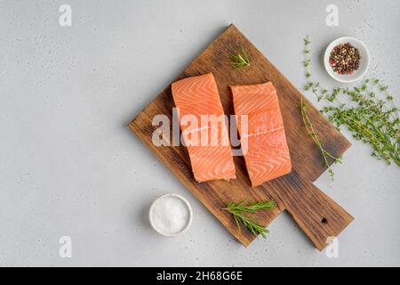 Filet de saumon scandinave frais brut.Romarin et thym.Sel et poivre.Sur une ancienne planche de bois.Fruits de mer Pescetarian pour la cuisine.Préparation de la nutrition Banque D'Images