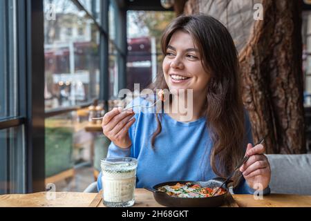 Une jeune femme dans un café dines sur le shakshuka traditionnel et ayran. Banque D'Images