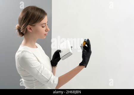 Le dermatologue cosmétologue possède un paquet de médicaments pour le rajeunissement du visage.Une femme médecin au bureau montre les options de traitement.Maquette avec copie Banque D'Images