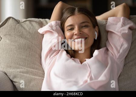 Souriante attrayante paisible jeune femme écoutant de la musique dans des écouteurs. Banque D'Images