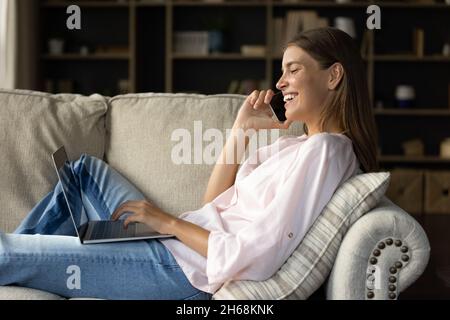 Souriante jeune femme belle multitâche à la maison. Banque D'Images