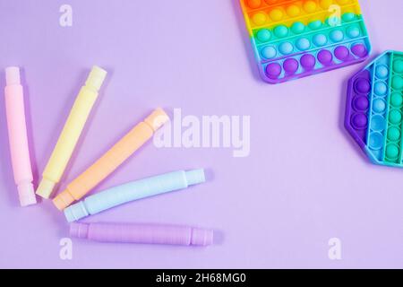 Tube ondulé en plastique coloré multicolore et pop-it sur fond violet.Figurine sensorielle anti-stress jouet en plastique 2021. Banque D'Images