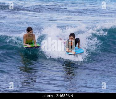 Honolulu, Hawaii - 6 novembre 2021 - les jeunes garçons jouent sur leurs planches de surf. Banque D'Images