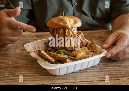 Honolulu, Hawaii - 6 novembre 2021 - l'homme montre un énorme hamburger avec des rondelles d'oignon. Banque D'Images