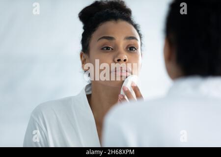 Bonne jeune femme africaine exfoliante visage avec éponge. Banque D'Images