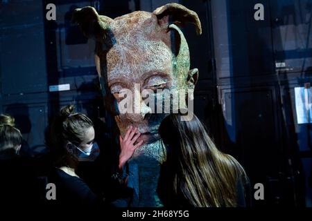 Munich, Allemagne.11 novembre 2021.Un membre de l'ensemble et des membres du personnel se tiennent à côté de la scène lors d'une répétition du ballet de conte de fées 'Cendrillon' au Théâtre national, en ajustant une grande tête de masque.Le travail de trois actes devrait avoir sa première allemande au Théâtre national le 19 novembre 2021.Credit: Sven Hoppe/dpa/Alay Live News Banque D'Images