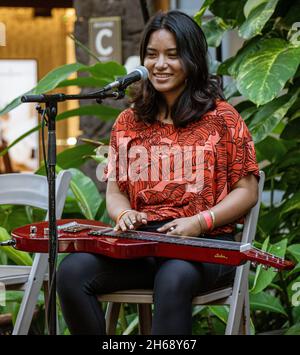 Waikiki, Honolulu, Hawaii - 6 novembre 2021 - la jeune femme joue de la guitare en acier comme divertissement de rue. Banque D'Images