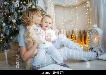 Enfant et mère en pyjama léger sur le fond d'un arbre de Noël. Banque D'Images