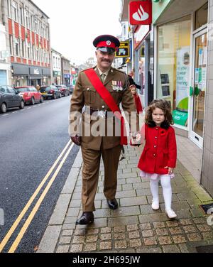 Camborne,Cornwall,UK,14 novembre 2021, Un homme en uniforme de l'armée marche avec un enfant en manteau rouge pour assister à un service de mémoire à Camborne, Cornwall, y compris, les Cadets de l'Air et le maire, Zoe Fox.La parade a défilé dans le centre-ville avant la couronne qui a été posée au mémorial et au service de l'église Camborne. Crédit : Keith Larby/Alay Live News Banque D'Images