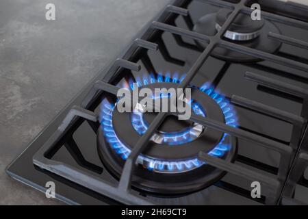 dessus de cuisinière à gaz avec flamme bleue sur surface de comptoir sombre Banque D'Images