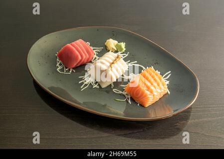 Le sashimi est un plat japonais qui se compose principalement de fruits de mer crus ou de poisson, finement coupés, mais pas autant qu'un carpaccio.Servi avec une sauce et Banque D'Images