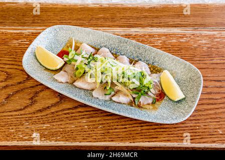 Le sashimi est un plat japonais qui se compose principalement de fruits de mer crus ou de poisson, finement coupés, mais pas autant qu'un carpaccio.Servi avec une sauce et Banque D'Images