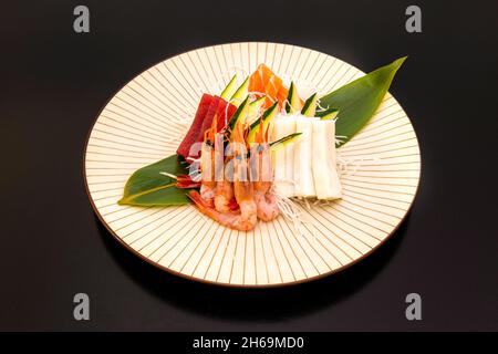 Le sashimi est un plat japonais qui se compose principalement de fruits de mer crus ou de poisson, finement coupés, mais pas autant qu'un carpaccio.Servi avec une sauce et Banque D'Images