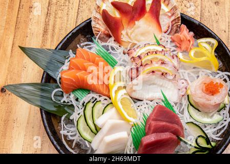 Le sashimi est un plat japonais qui se compose principalement de fruits de mer crus ou de poisson, finement coupés, mais pas autant qu'un carpaccio.Servi avec une sauce et Banque D'Images