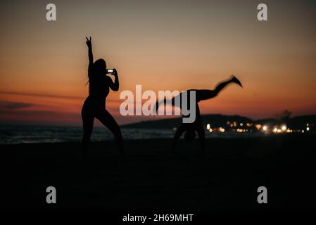 Une silhouette d'un couple fou posé sur une plage avec un fond de beau coucher de soleil. Banque D'Images