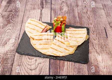 Savourez la saveur de cette quesadilla farcie de fromage et de jambon cuit au pico de gallo sur une table en bois Banque D'Images