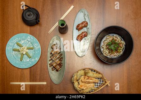 Nouilles japonaises, os de porc ou de poulet et différents légumes, pâte miso, sauce soja, nouilles udon, crevettes tempura,rouleau uramaki, nigiri de saumon, tapis Banque D'Images