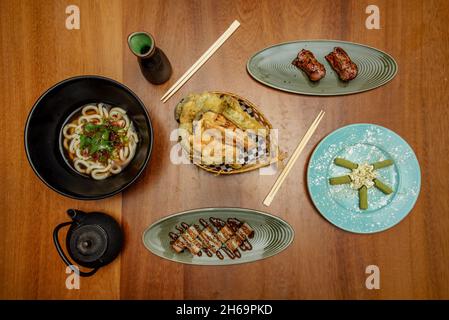 Nouilles japonaises, os de porc ou de poulet et différents légumes, pâte miso, sauce soja, nouilles udon, crevettes tempura,rouleau uramaki, nigiri de saumon, tapis Banque D'Images