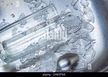 verre et cuillère en forme de ventre parmi les éclats de plats cassés dans l'évier de cuisine pour laver la vaisselle Banque D'Images