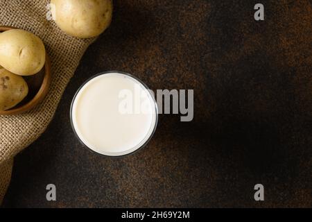 Lait de pomme de terre et pomme de terre végétaliens sur fond marron.Produit de remplacement du lait à base de plantes et sans lactose.Vue de dessus. Banque D'Images