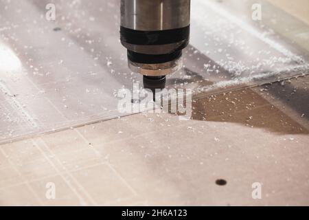 La fraise à rainurer traite la feuille de plastique transparente sur une fraiseuse CNC, photo rapprochée avec mise au point douce sélective Banque D'Images