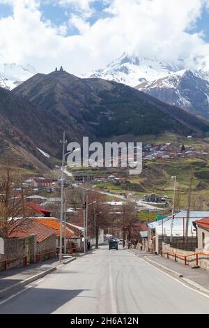 Stepantsminda, Géorgie - 1er mai 2019 : vue sur la rue Stepantsminda par temps ensoleillé, paysage de montagne géorgien avec église de la Trinité de Gergeti sur un backgroun Banque D'Images