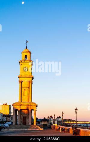 La tour de l'horloge sur le front de mer déserté de la station balnéaire de Herne Bay.Tour revêtue de pierre en début de matinée, à l'heure d'or, contre un ciel bleu clair. Banque D'Images