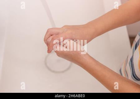 garçon lave les mains sous l'eau courante dans la salle de bains.Gros plan des paumes dans le cadre Banque D'Images