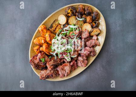 morceaux de viande barbecue kebabs porc grillé et boeuf et poulet sur une assiette avec oignons et légumes et pommes de terre dans un restaurant Banque D'Images