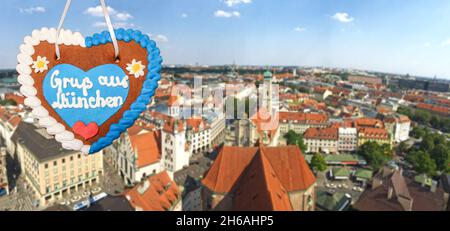 Focus sur le coeur de pain d'épice avec le slogan écrit "Greetings from Munich" - horizon flou avec la vieille ville de Munich centre avec Marienplatz, Bavière Banque D'Images