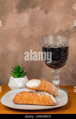 deux cannolis à la crème servis avec un verre de vin Banque D'Images