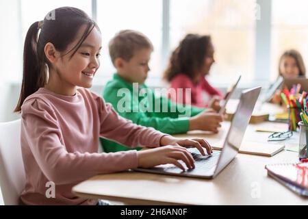 Formation en ligne.Divers enfants utilisant un ordinateur portable dans la classe moderne à l'école, concentration sélective sur la bonne école asiatique naviguant sur Internet sur ordinateur. Banque D'Images