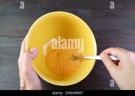 Les mains du Mans tiennent le bol à mélanger tout en battant les œufs pour la cuisson Banque D'Images