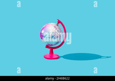 Un globe fait d'une grande boule de Noël brillante disco sur un stand rose.Tous les habitants du monde célèbrent le concept du nouvel an.Noël universel ou N Banque D'Images