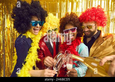 Groupe de heureux divers amis dans les perruques drôles boire et s'amuser à la fête de boîte de nuit Banque D'Images