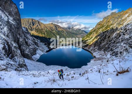 High Tatras, Pologne - 10 16 2021: Grimpeur sur le chemin du pic de Rysy à High Tatras, avec la Czarny Staw (alias Black Lake) en arrière-plan. Banque D'Images