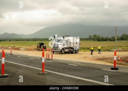 De MacKay à Townsville Bruce Highway, Queensland, Australie - novembre 2021 : deux travailleurs de la route marchent à côté d'un camion et de machinerie lourde faisant des travaux de terrassement sur hi Banque D'Images