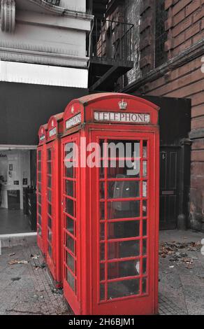 Trois anciennes boîtes téléphoniques rouges de communication dans une ligne sur une rue urbaine au Royaume-Uni Banque D'Images