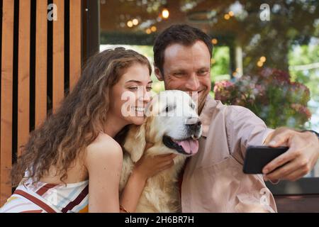 Portrait d'un jeune couple prenant selfie avec un chien à l'extérieur en été, espace de copie Banque D'Images