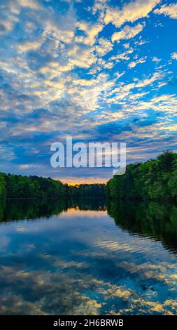 Lever de soleil sur un horizon de ciel nuageux avec réflexion dans le lac Banque D'Images