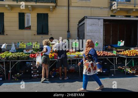 Les gens achètent des aliments frais dans une cabine de fruits et légumes au marché hebdomadaire dans le centre-ville d'Alassio en été, Savona, Ligurie, Italie Banque D'Images