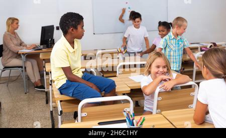 Tween garçons et filles amical parler en pause dans la salle de classe Banque D'Images