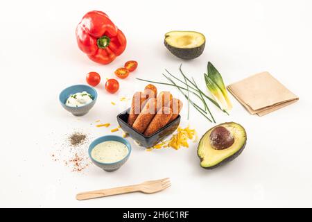 Tequeños vénézuélien farcis avec du fromage frais et des sauces à trempette, avec de l'avocat, du poivron rouge et des tomates cerises Banque D'Images