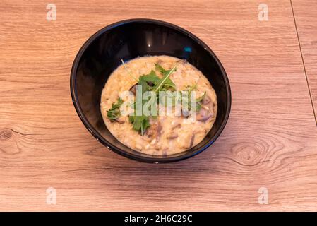 Risotto aux champignons, un plat typique du nord de l'Italie, fait avec des champignons porcini recouverts de feuilles d'arugula Banque D'Images